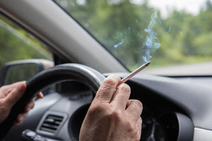 Man smoking a cigarette at the wheel of a car.