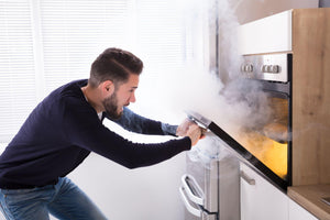 Shocked man looking at burnt cookies in oven